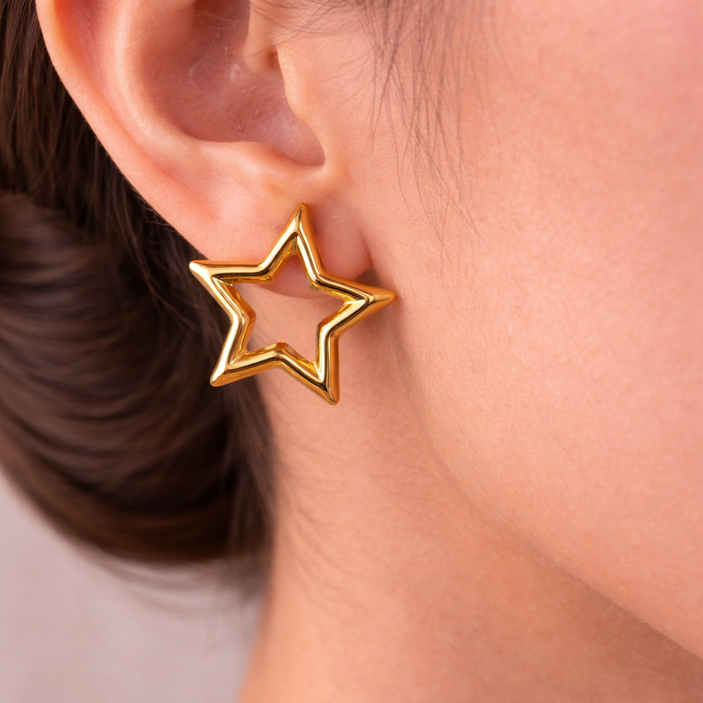 Gold star-shaped earring worn by a person with a neutral background