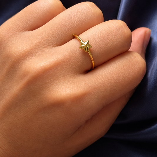 Gold star-shaped ring on a hand with dark blue fabric background