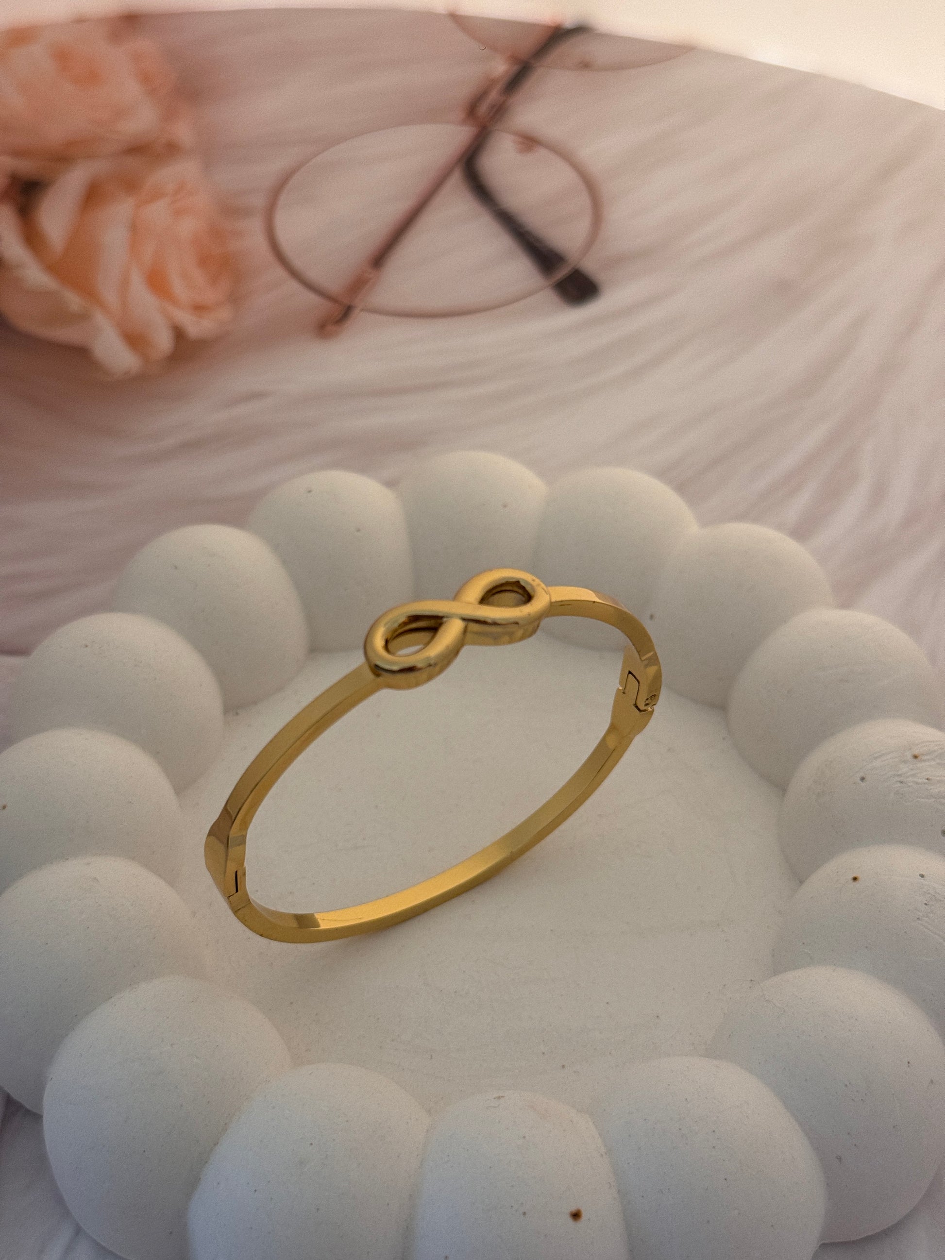 Gold bracelet with a unique design on a textured white surface