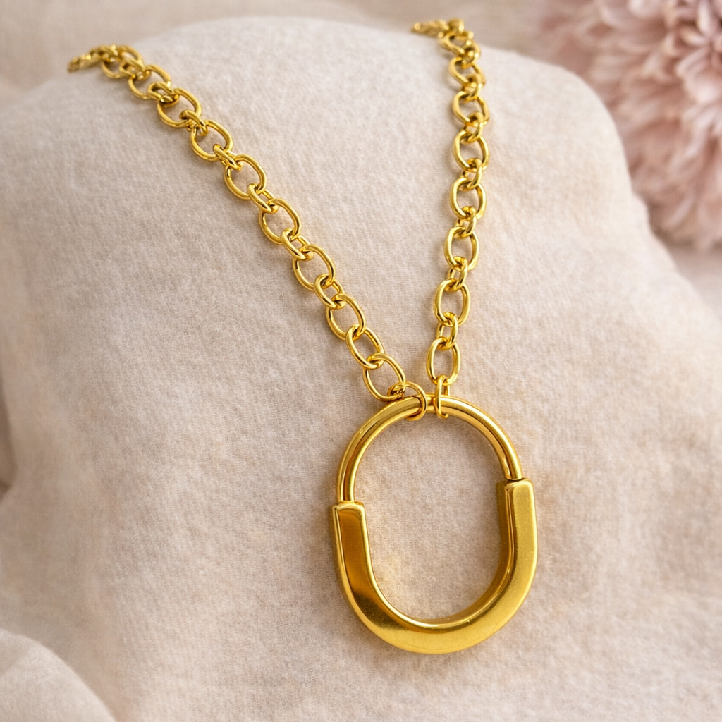 Gold necklace with a unique pendant on a soft beige background