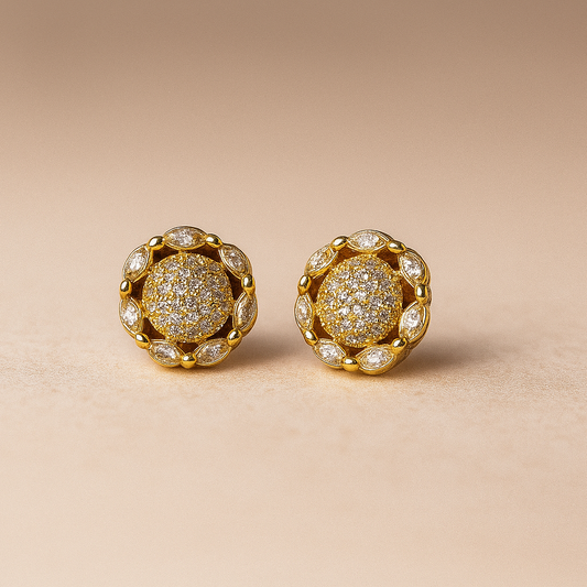 Pair of gold earrings with diamond-like stones on a beige background