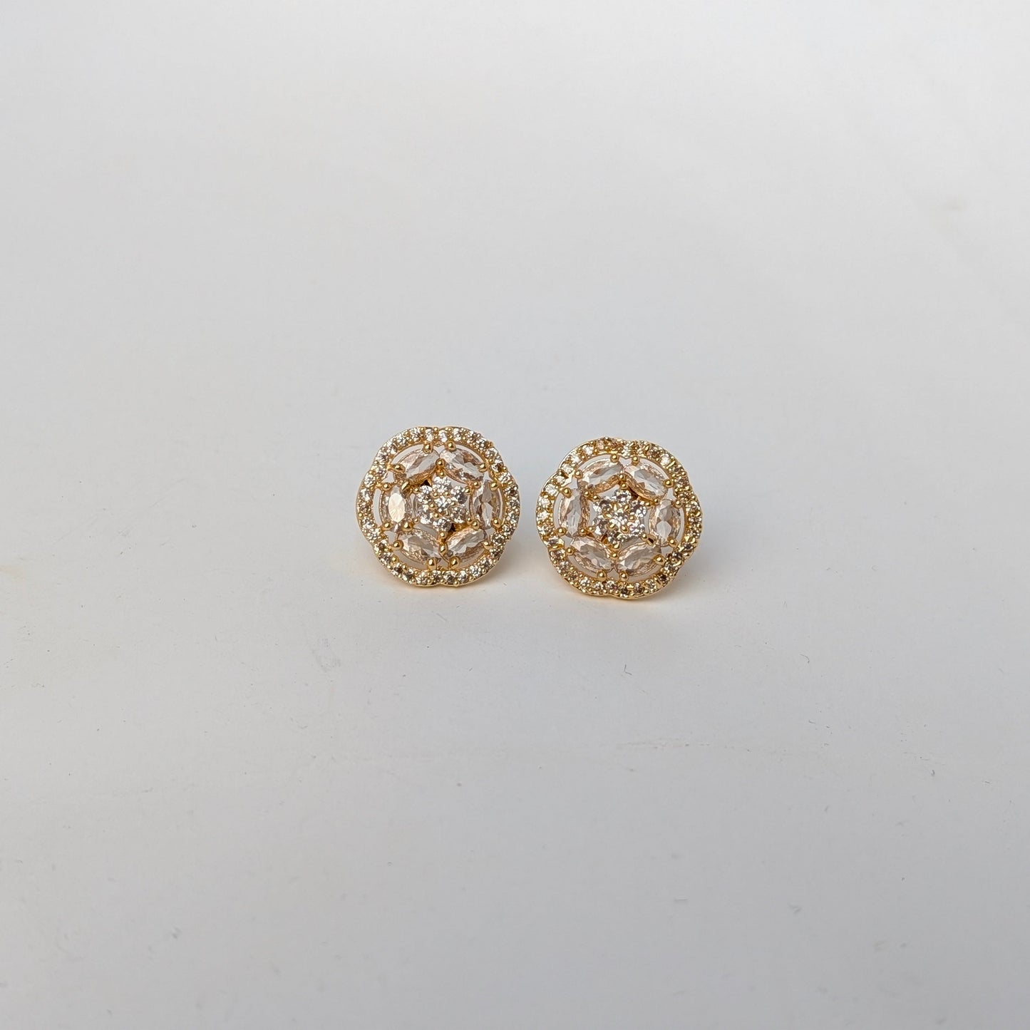 Gold earrings with intricate design on a light gray background