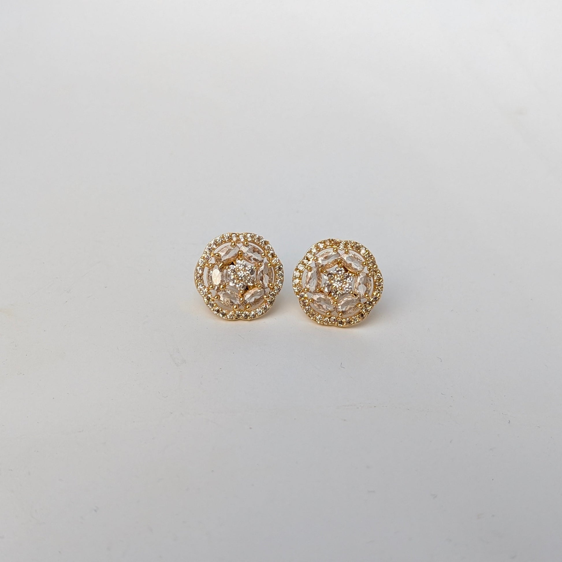 Gold earrings with intricate design on a light gray background