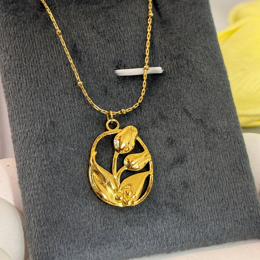 Gold necklace with a floral pendant on a gray surface