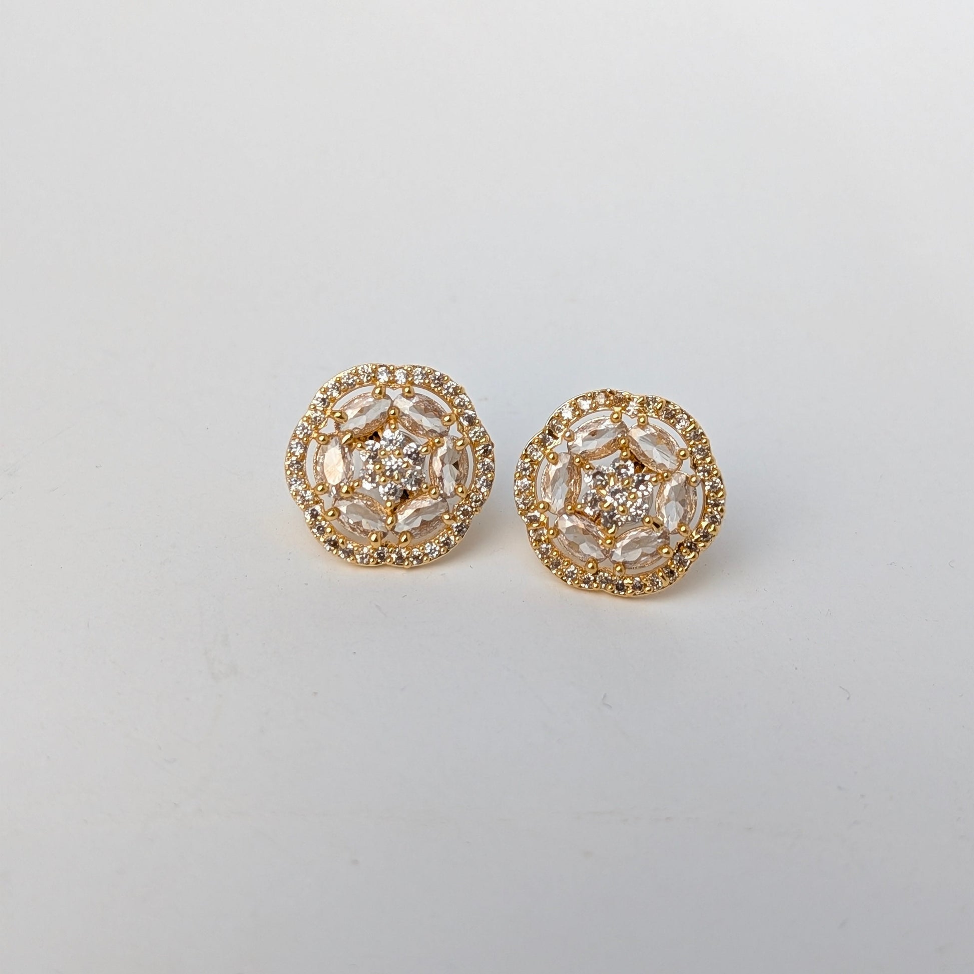 Pair of gold floral earrings on a light gray background