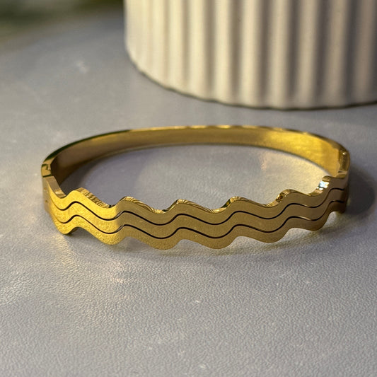 Gold ring with wavy pattern on a metallic surface