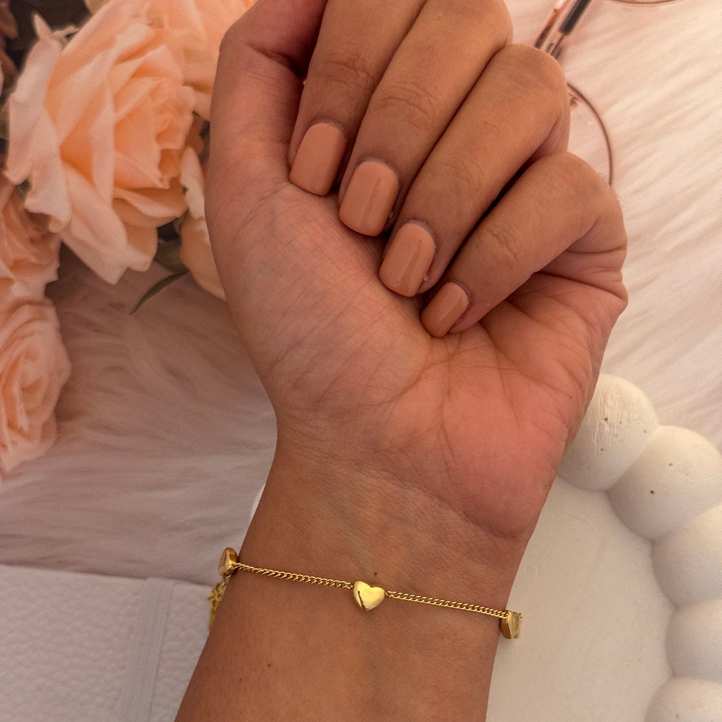 Hand holding glasses with a gold bracelet on a blurred floral background