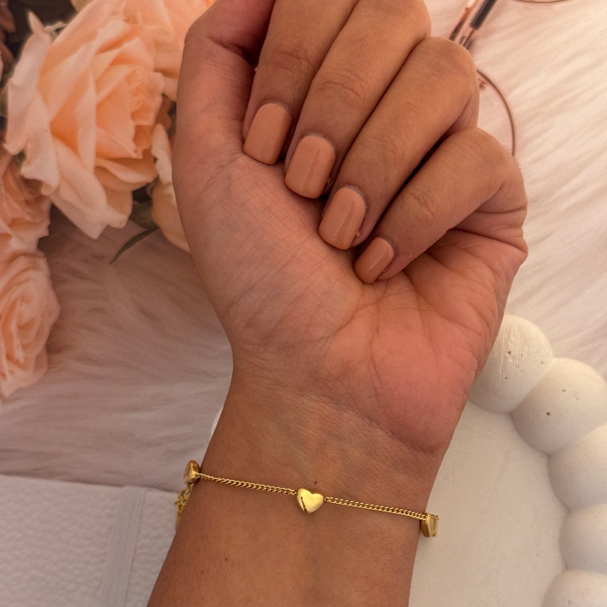 Hand holding glasses with a gold bracelet on a blurred floral background