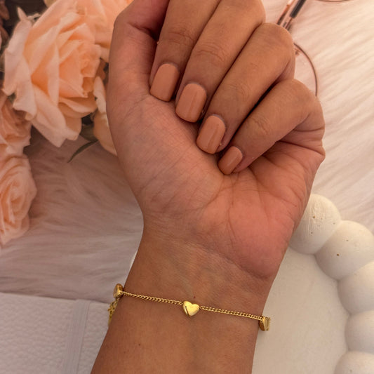 Hand holding glasses with a gold bracelet on a blurred floral background