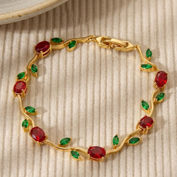 Gold bracelet with red and green gemstones on a textured beige surface