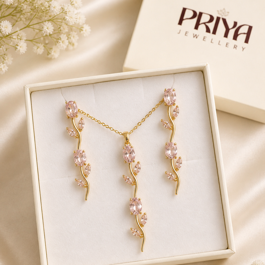Gold floral earrings in a box with 'Priya Jewellery' branding on a beige fabric background.