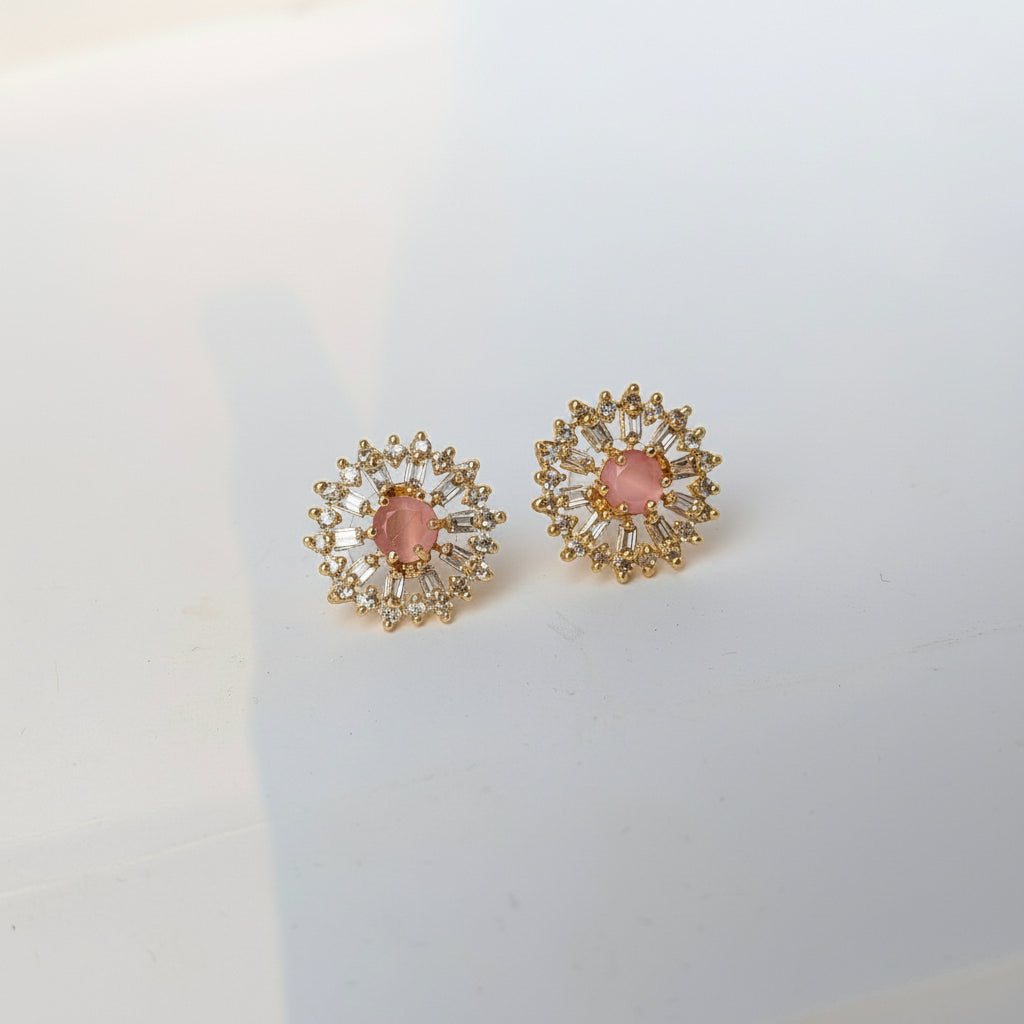 Pair of gold earrings with pink gemstones on a white background