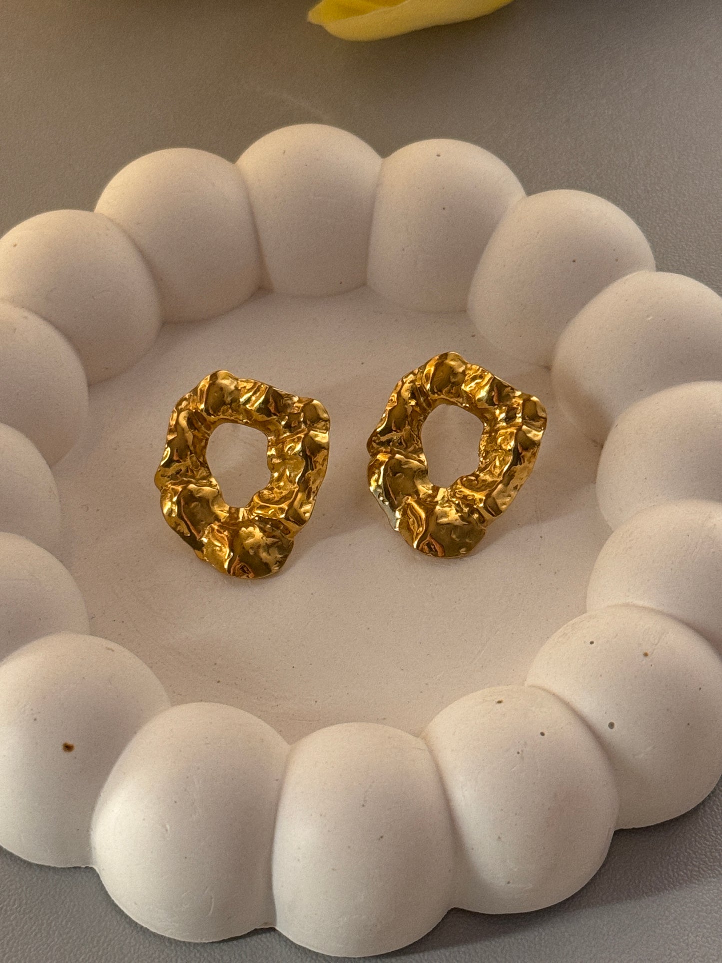 Gold earrings on a white stone surface