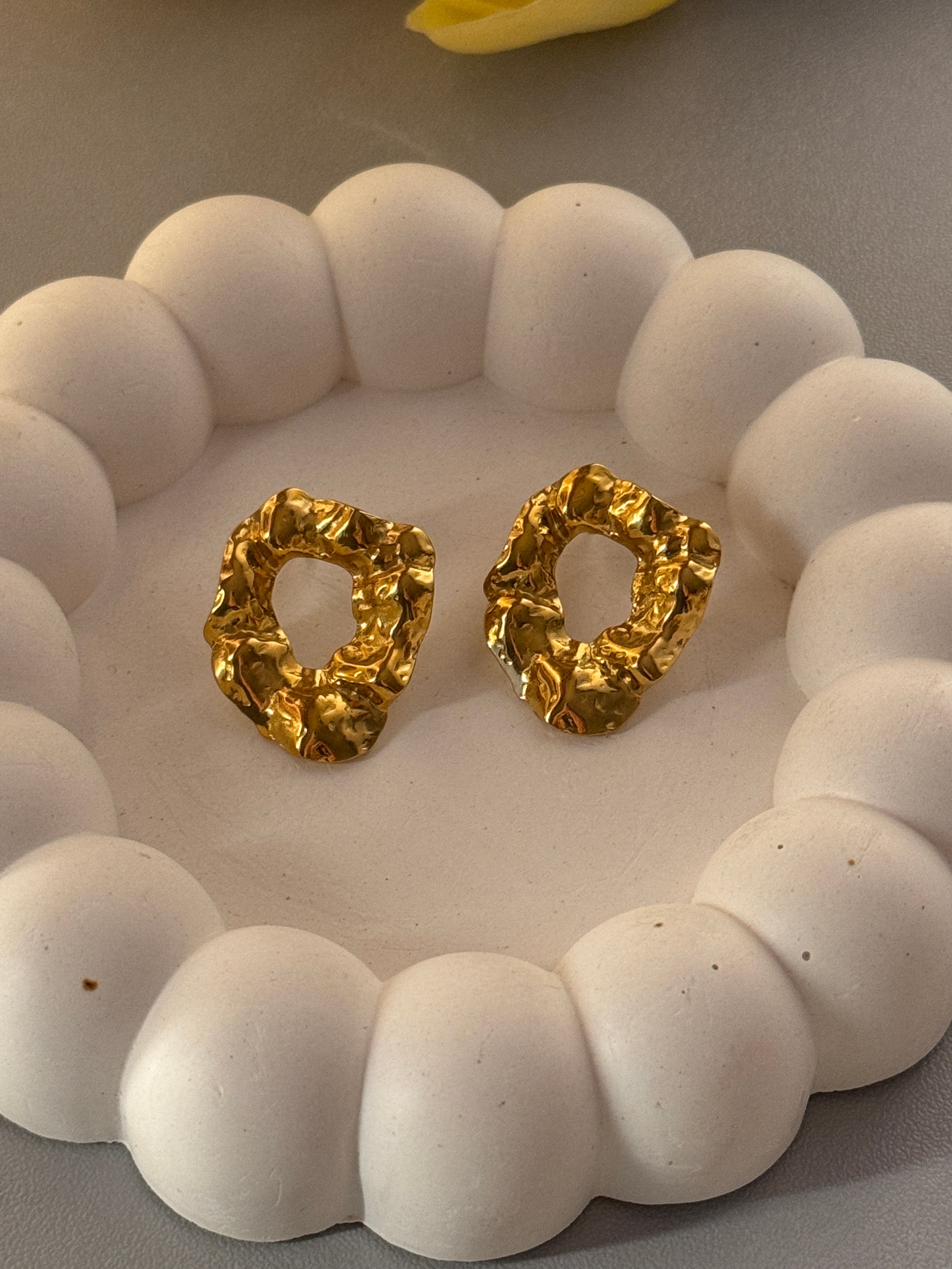 Gold earrings on a white stone surface