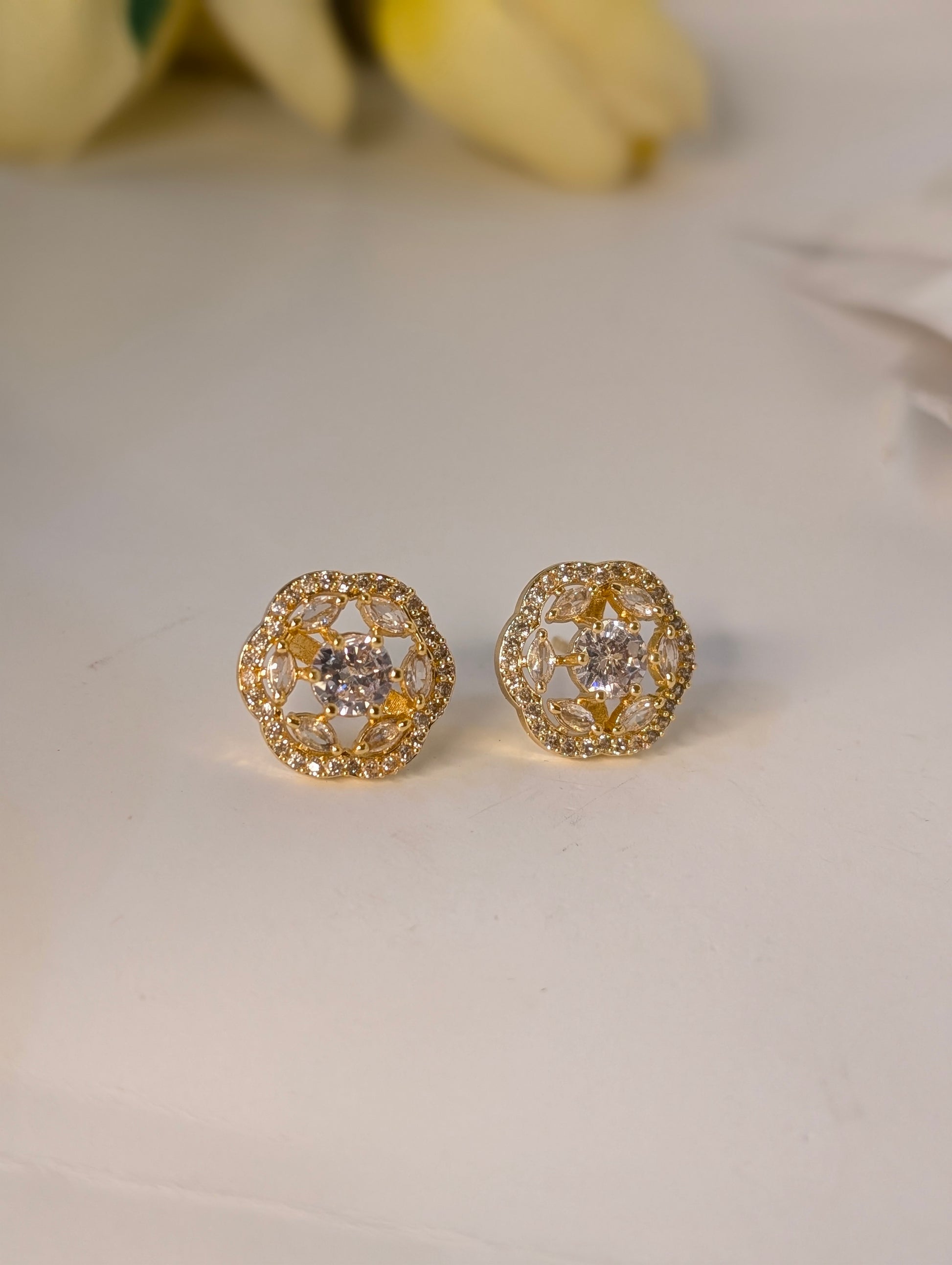 Gold earrings with diamond-like stones on a light background