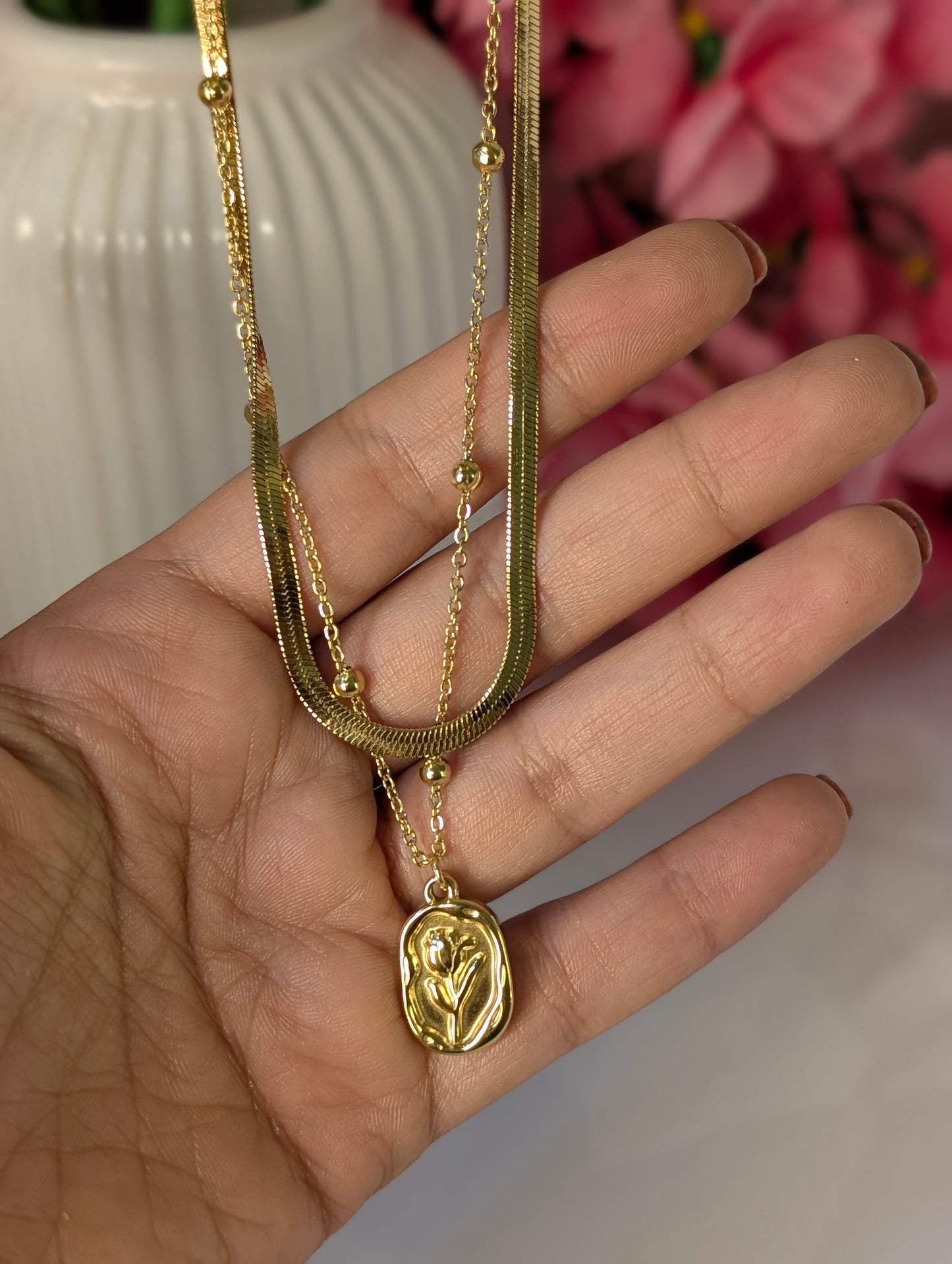 Gold necklace with a pendant held in a hand against a blurred background