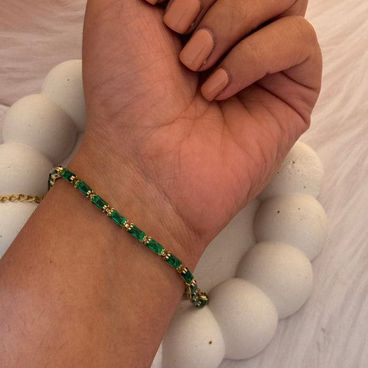 Hand wearing a green beaded bracelet with a blurred background