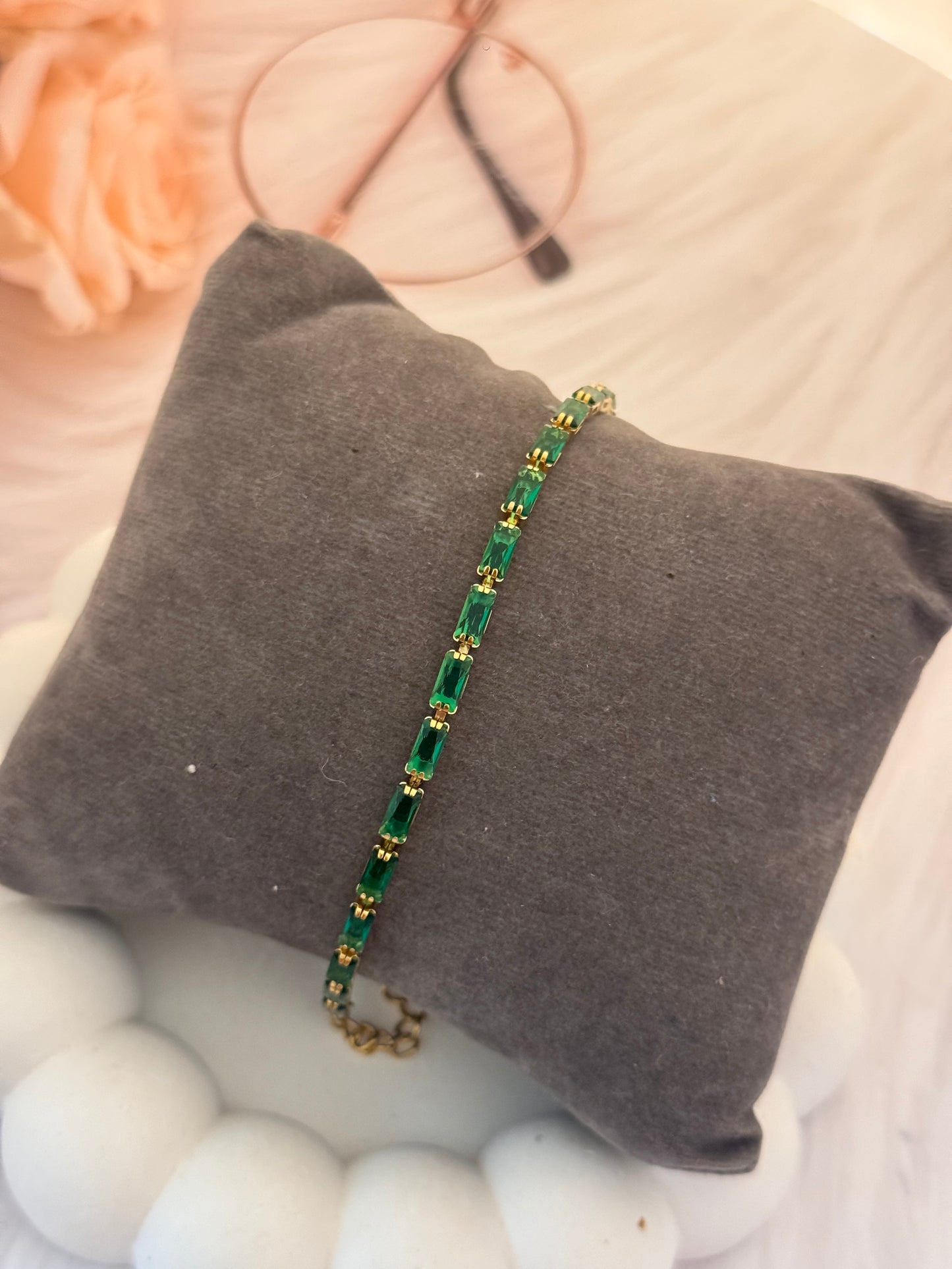 Green beaded bracelet on a gray pillow with blurred background