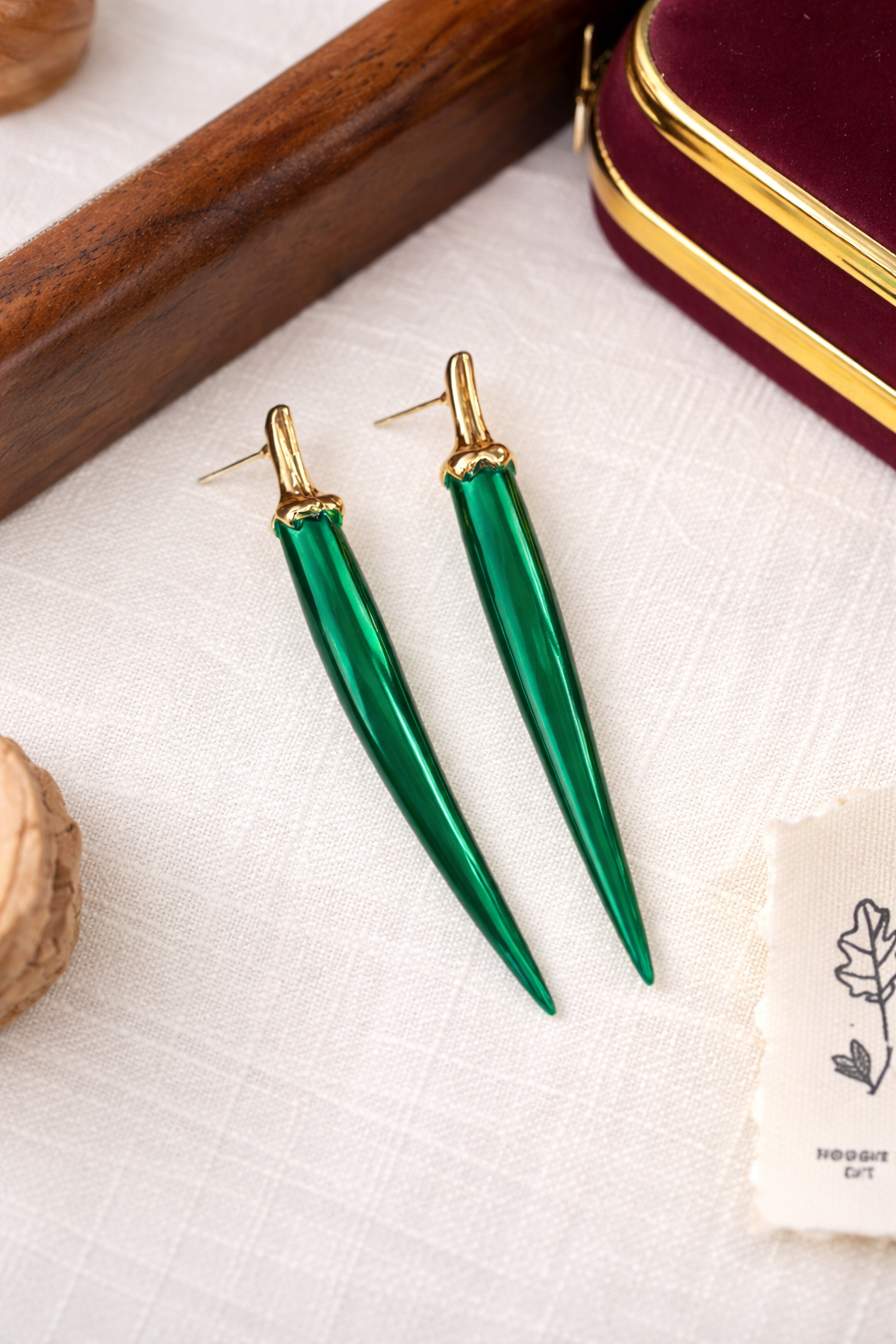 Green earrings with gold accents on a white fabric background