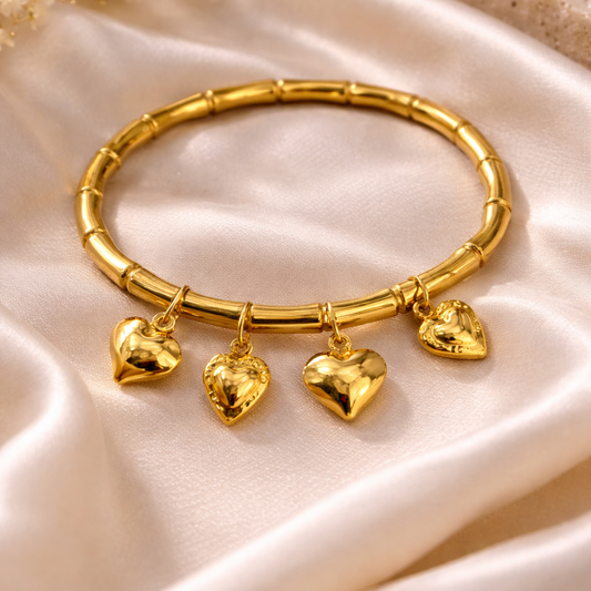Gold bracelet with heart-shaped charms on a beige fabric background