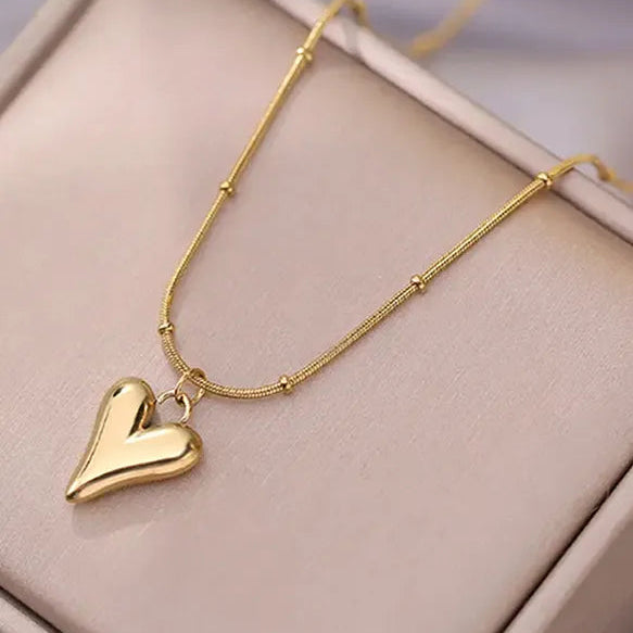 Gold heart-shaped pendant necklace on a beige surface