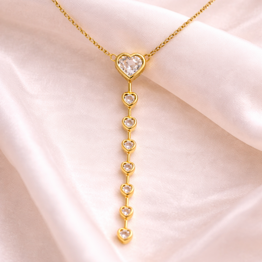 Gold necklace with a heart-shaped pendant on a pink fabric background