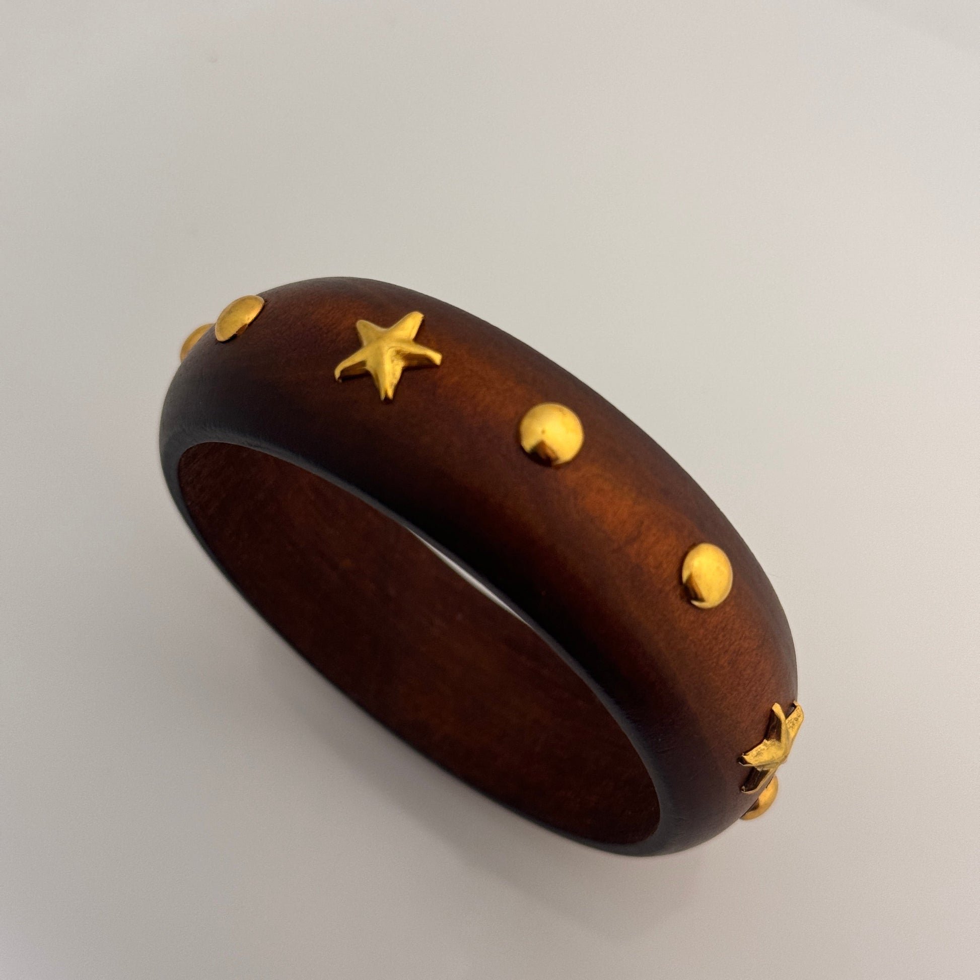 Wooden bracelet with gold star accents on a light gray background