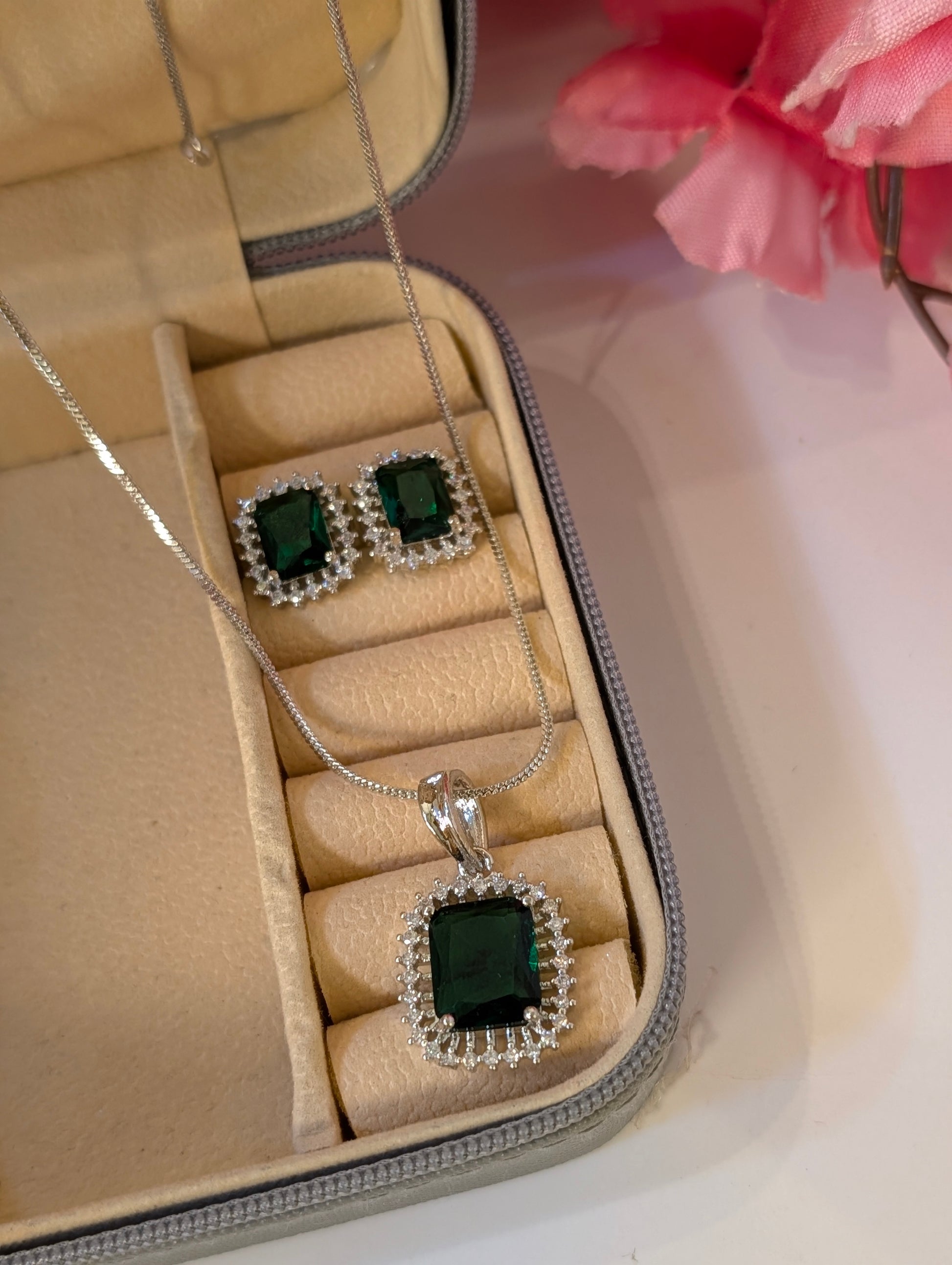 Jewelry set with green gemstones in a beige jewelry box.