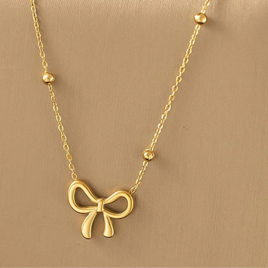 Gold bow-shaped necklace on a beige background