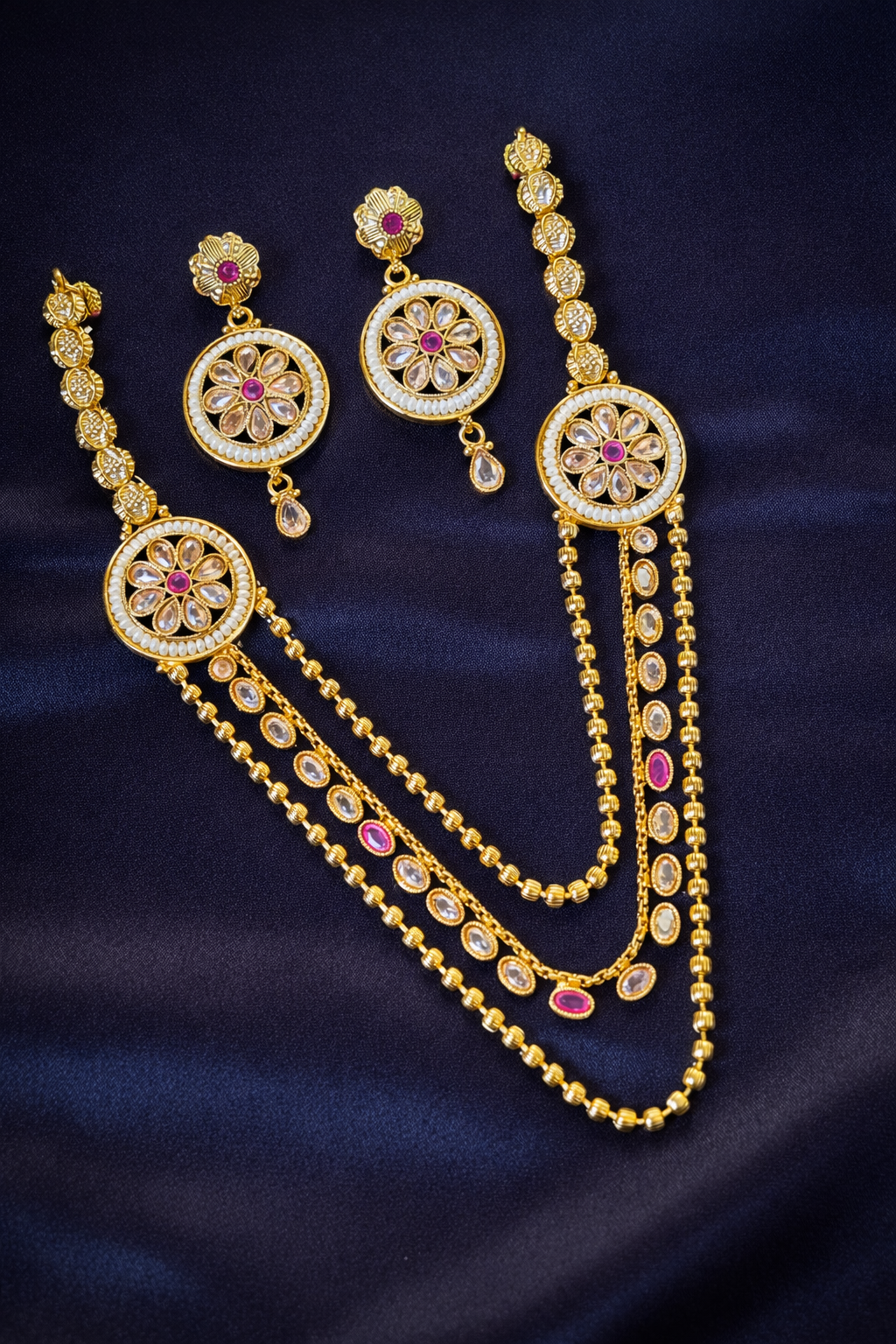 Gold jewelry set with earrings and necklace on a dark blue fabric background