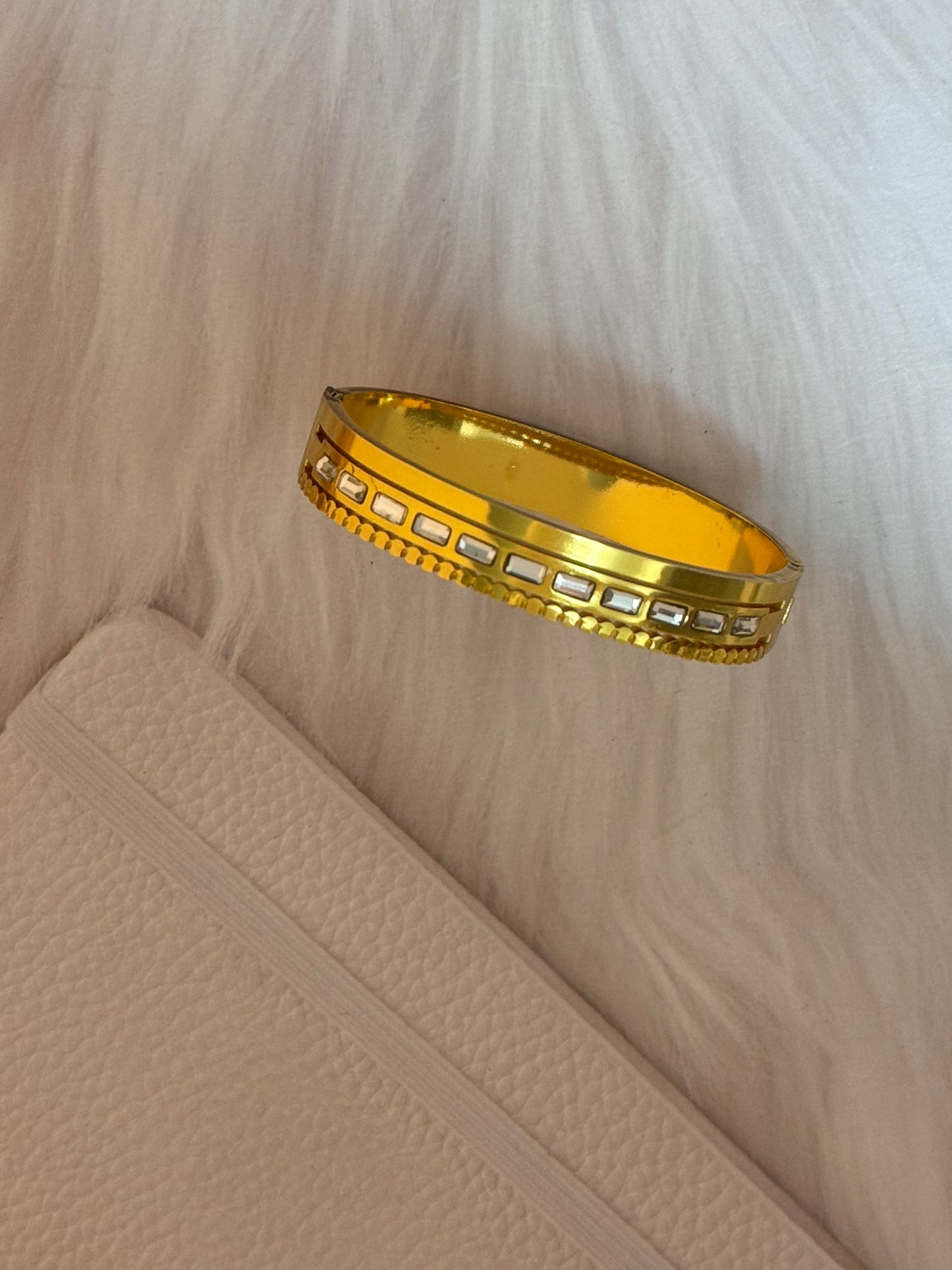 Gold bracelet with intricate design on a beige fabric background