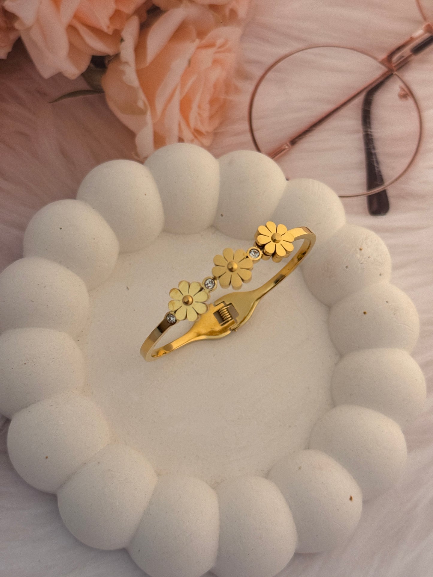 Gold bracelet with floral designs on a white beaded background