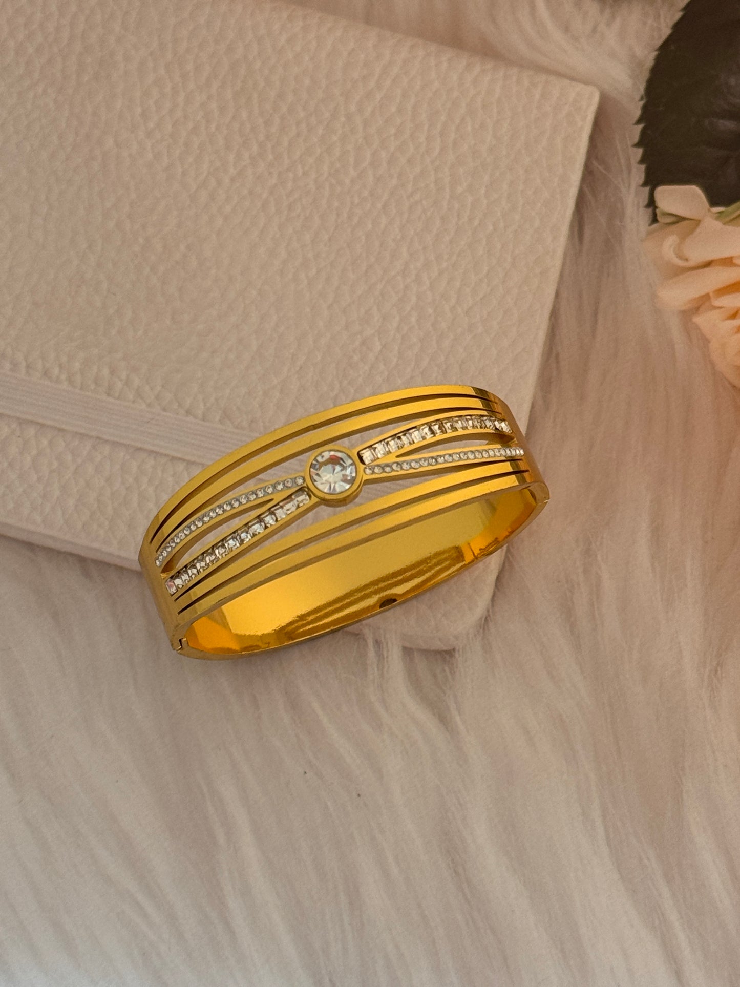 Gold Bracelet with diamond accents on a textured beige surface