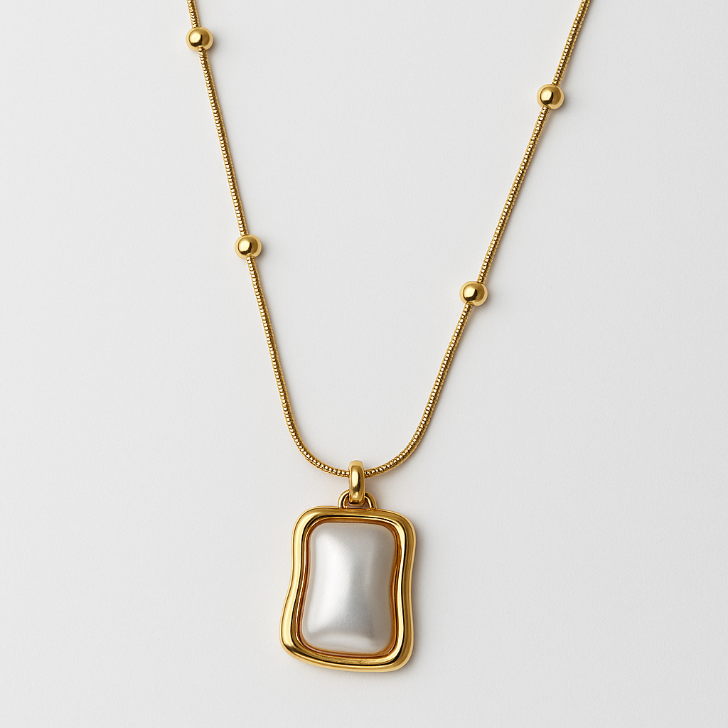 Gold necklace with a large pearl pendant on a light gray background