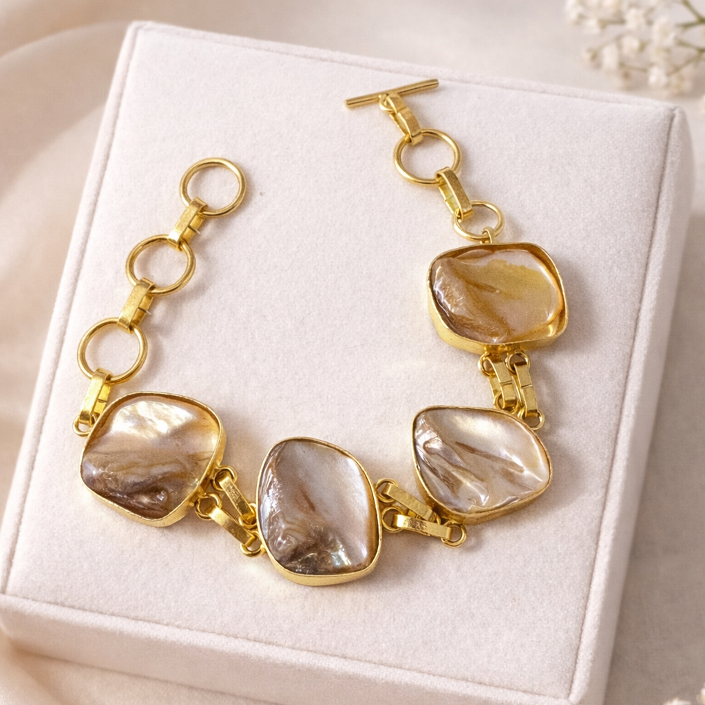 Gold bracelet with stone accents on a white box with flowers around