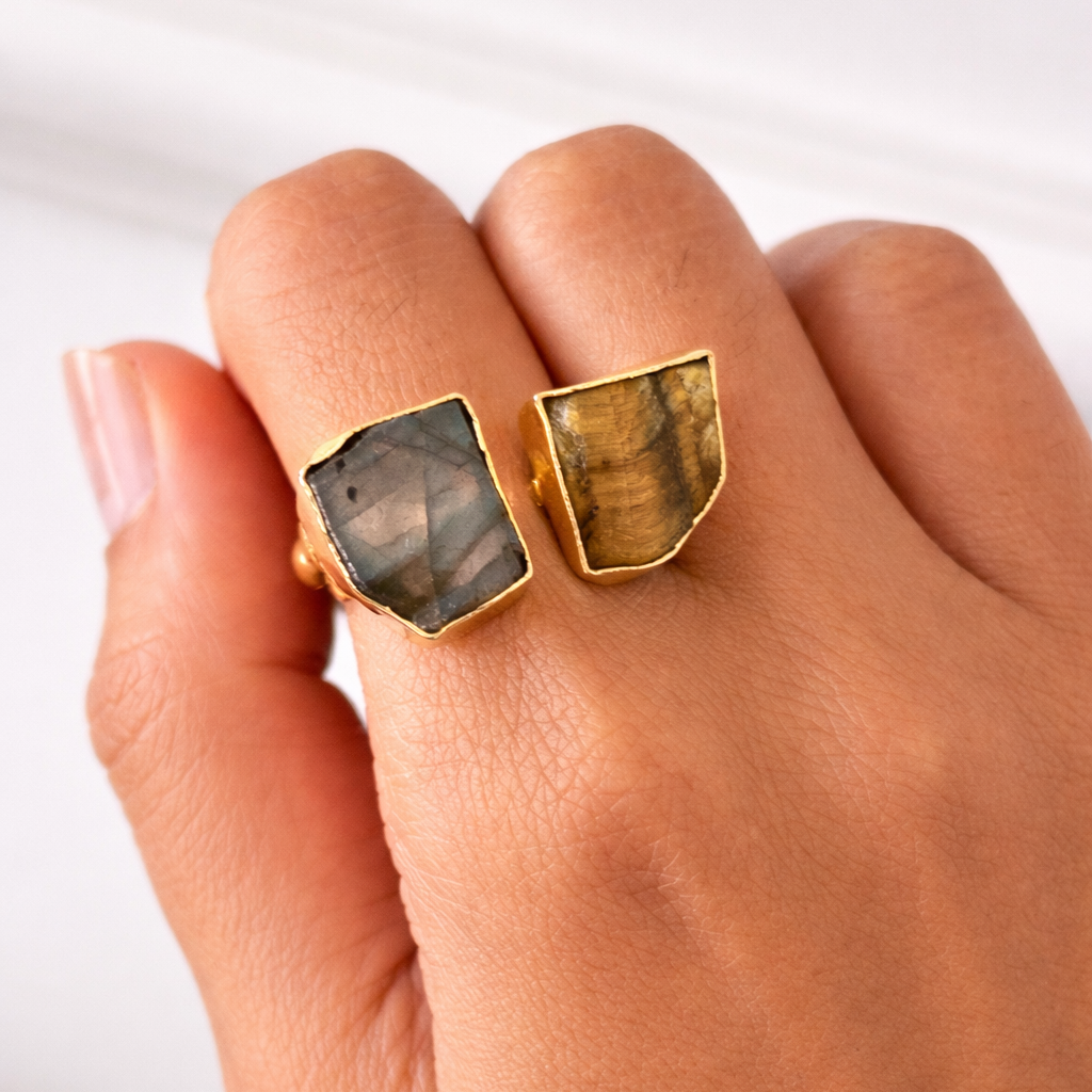 Gold ring with stone inlays on a hand against a white background