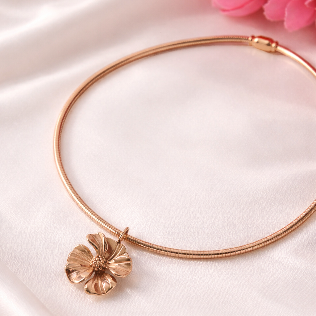 Rose gold bracelet with a floral pendant on a soft pink fabric background