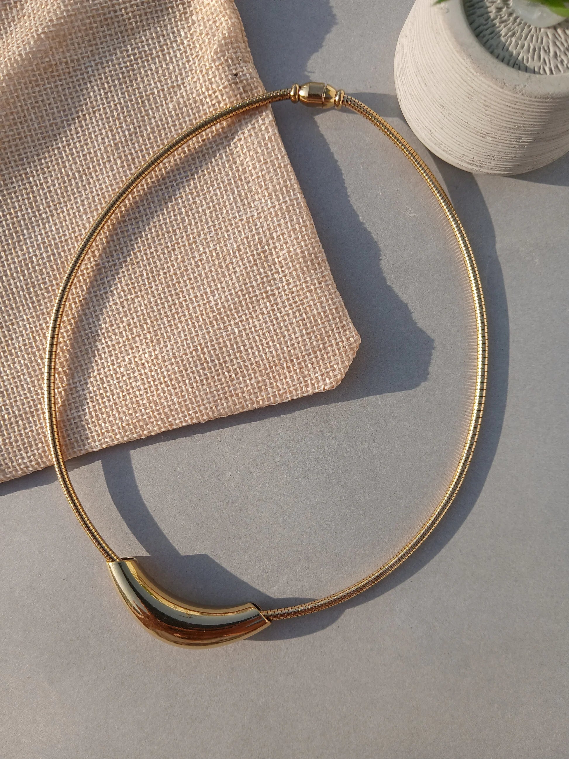 Gold necklace on a textured surface with a neutral background