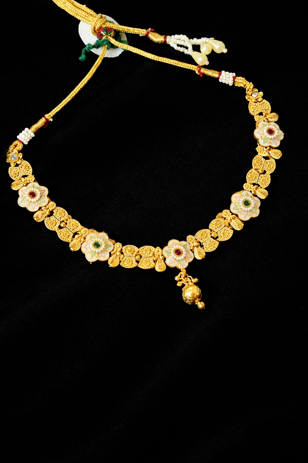 Gold necklace with floral designs on a black background