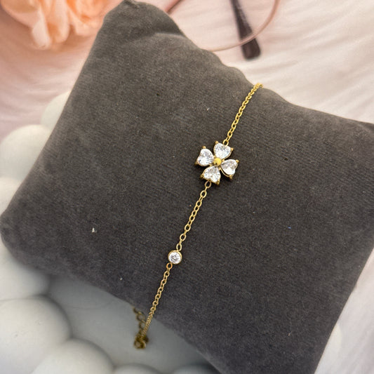Gold bracelet with floral design on a gray pillow