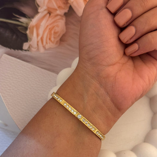 Gold bracelet on a wrist with a soft focus background