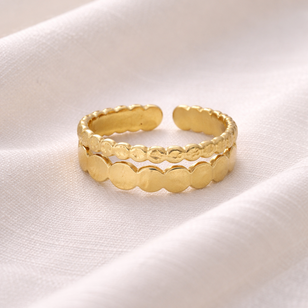Gold ring with a textured design on a white fabric background