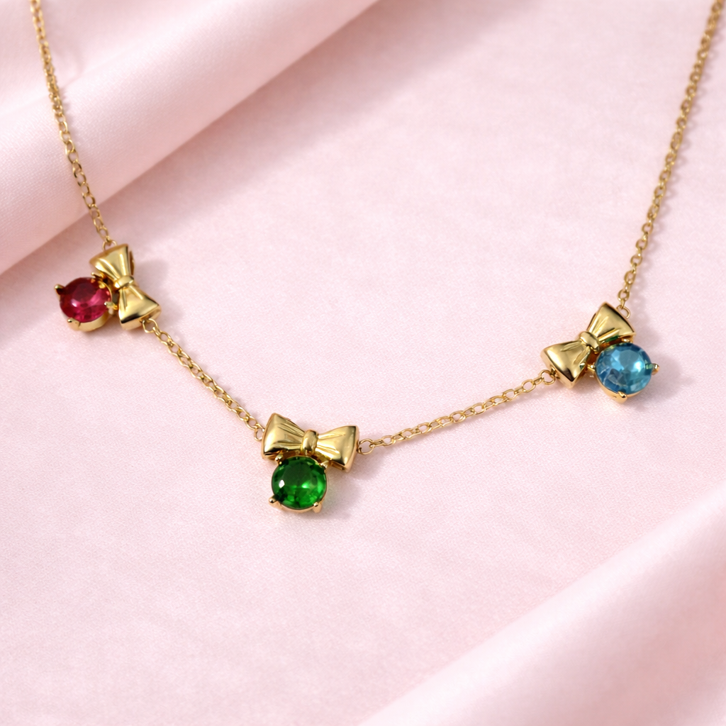 Necklace with gold bows and colored gemstones on a pink background
