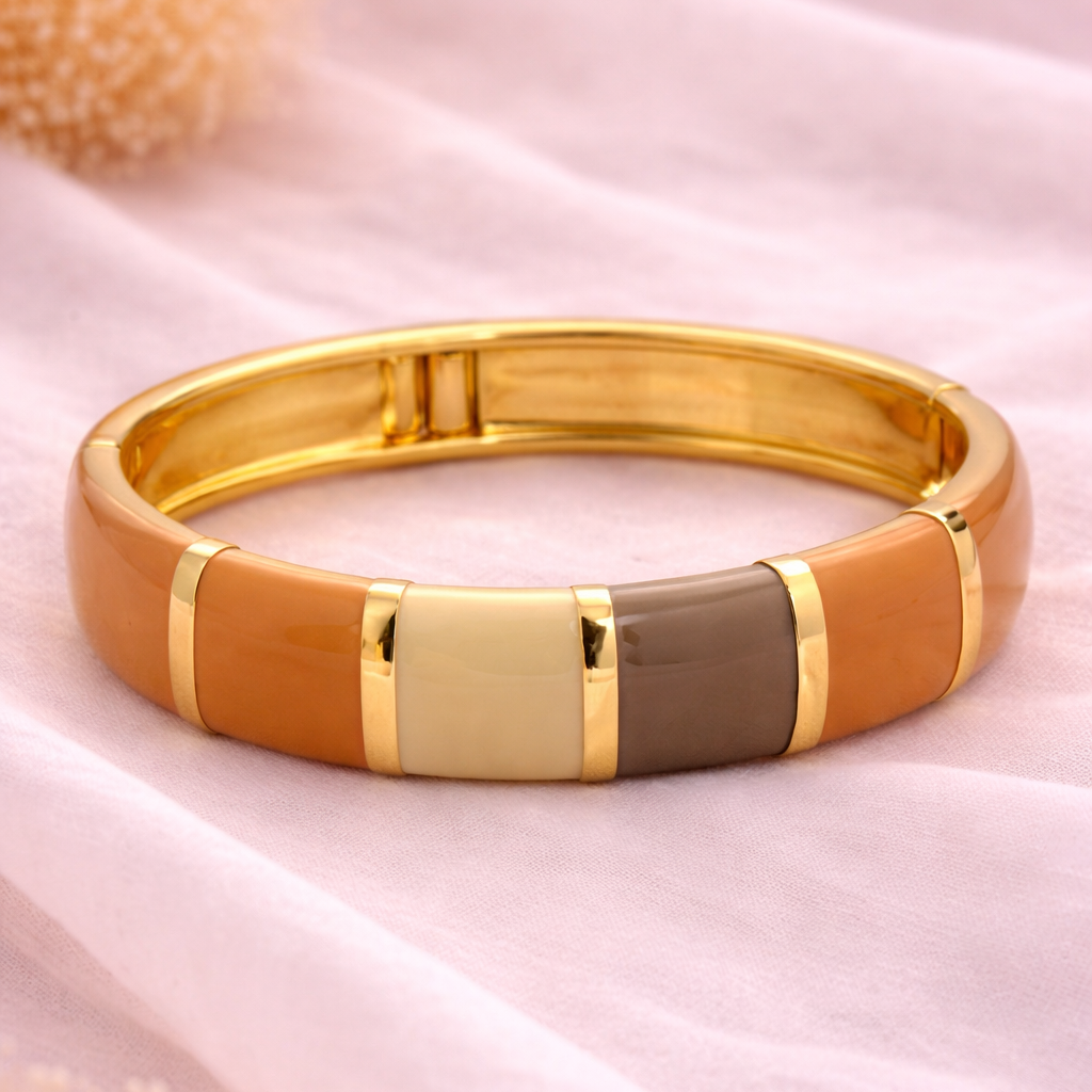Gold, brown, and beige bracelet on a pink fabric background