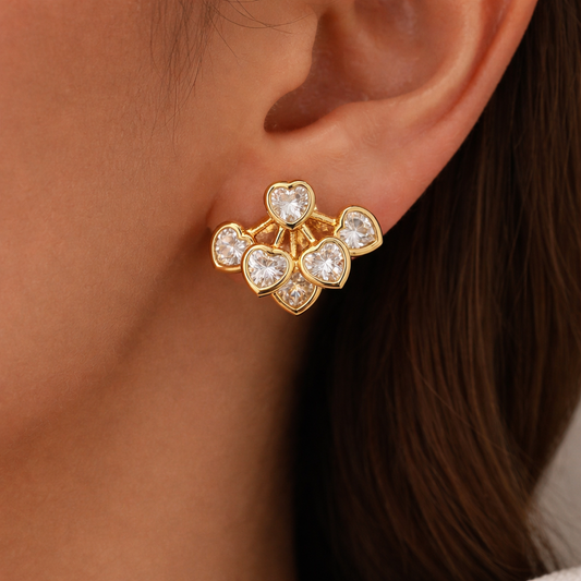 Gold heart-shaped earring worn by a person with dark hair.