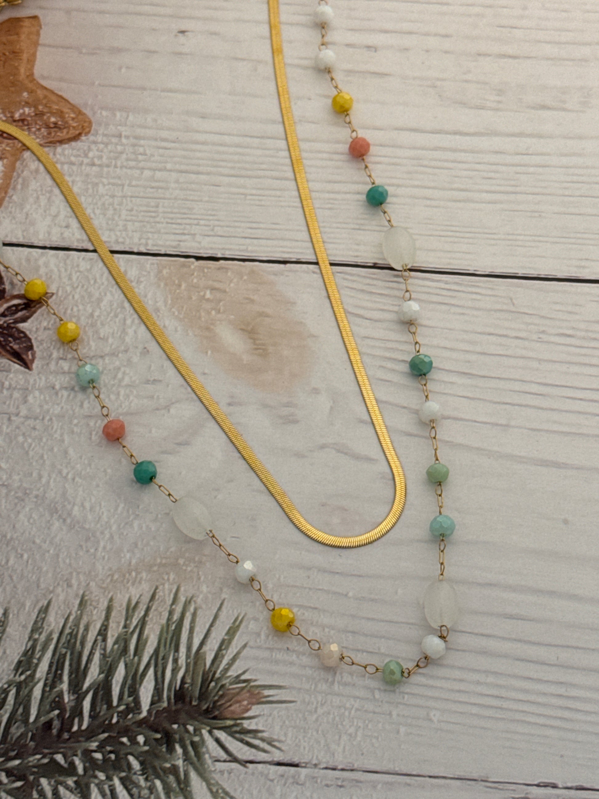 Decorative beaded chain with colorful beads on a wooden surface with a gold hanger.