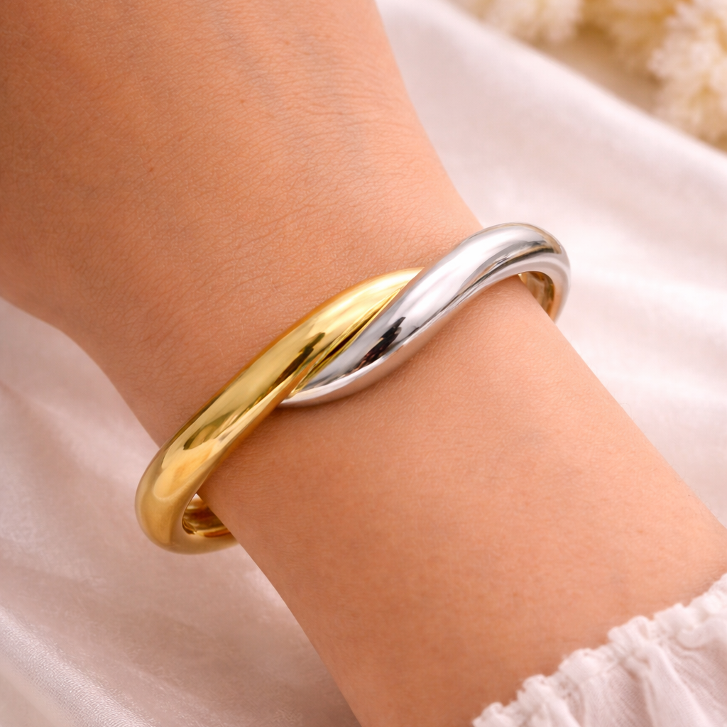 Two-toned gold and silver bracelet on a wrist with a soft background