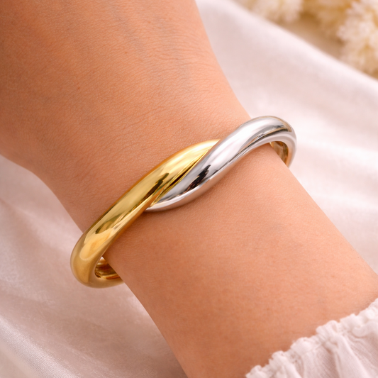 Two-toned gold and silver bracelet on a wrist with a soft background
