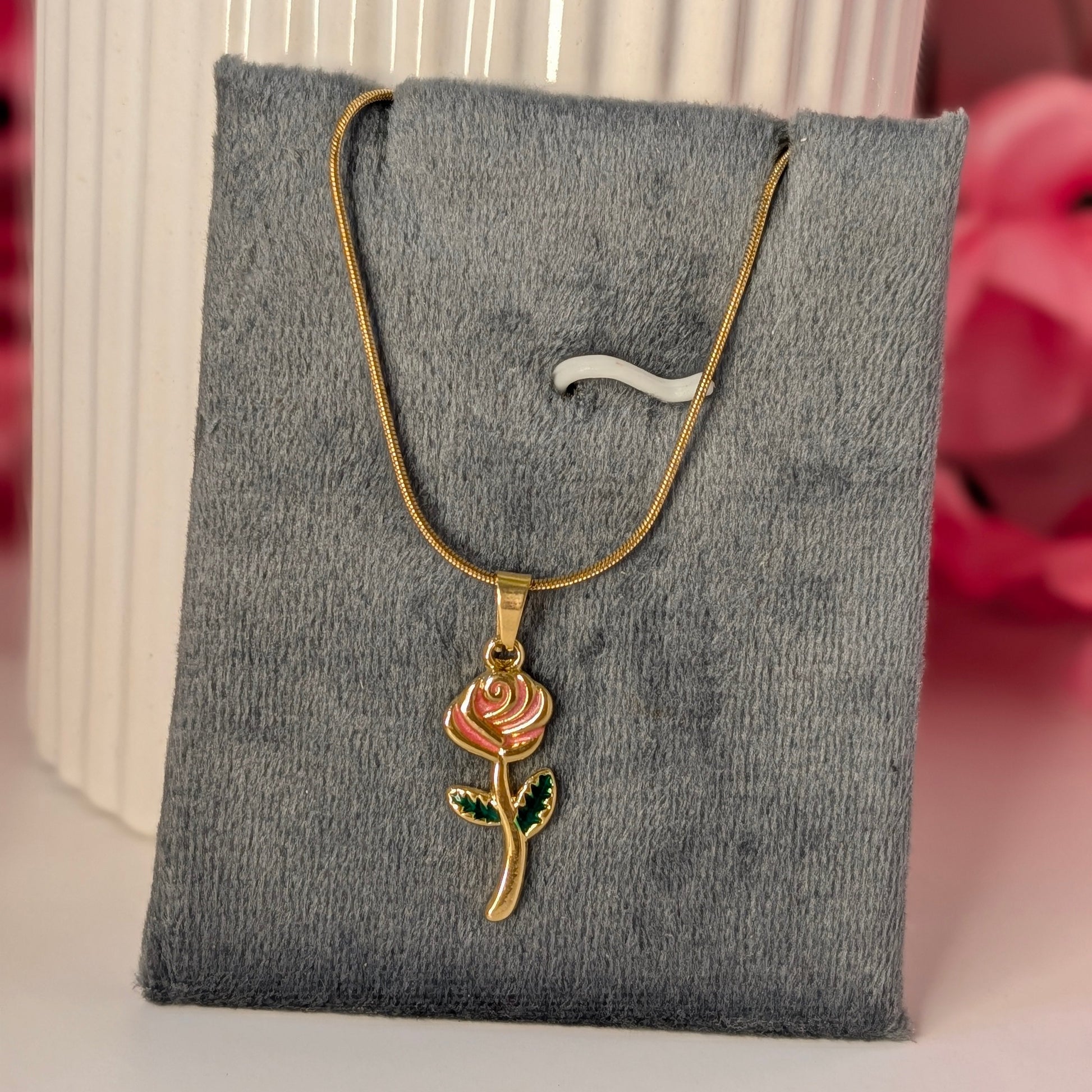 Gold necklace with a rose pendant on a gray jewelry display