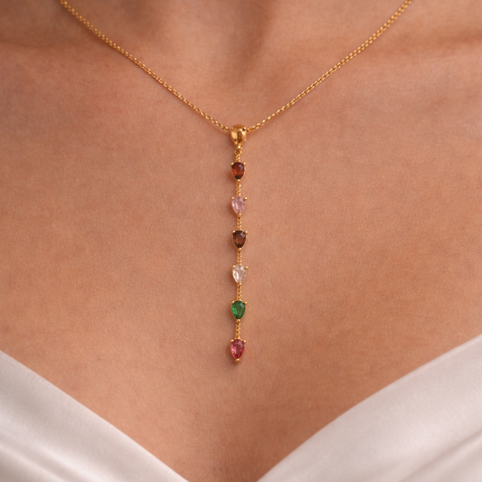 Gold necklace with gemstones on a person wearing a white top